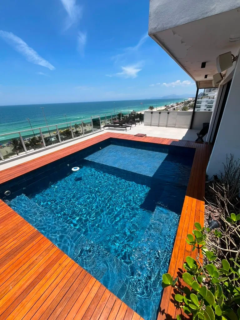 Piscina em cobertura com deck de madeira, vista para o mar e água cristalina